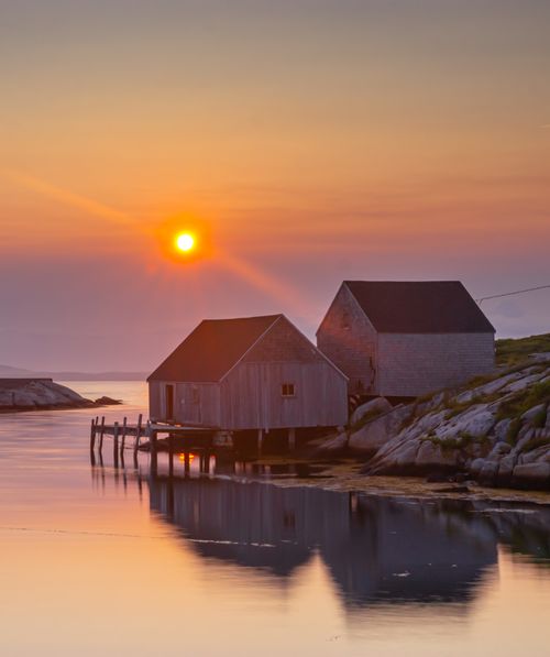 Free Idyllic scene of wooden houses at sunset by a calm river. Stock Photo