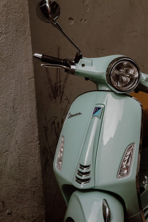 Teal Motor Scooter Parked Beside Brown Brick Wall