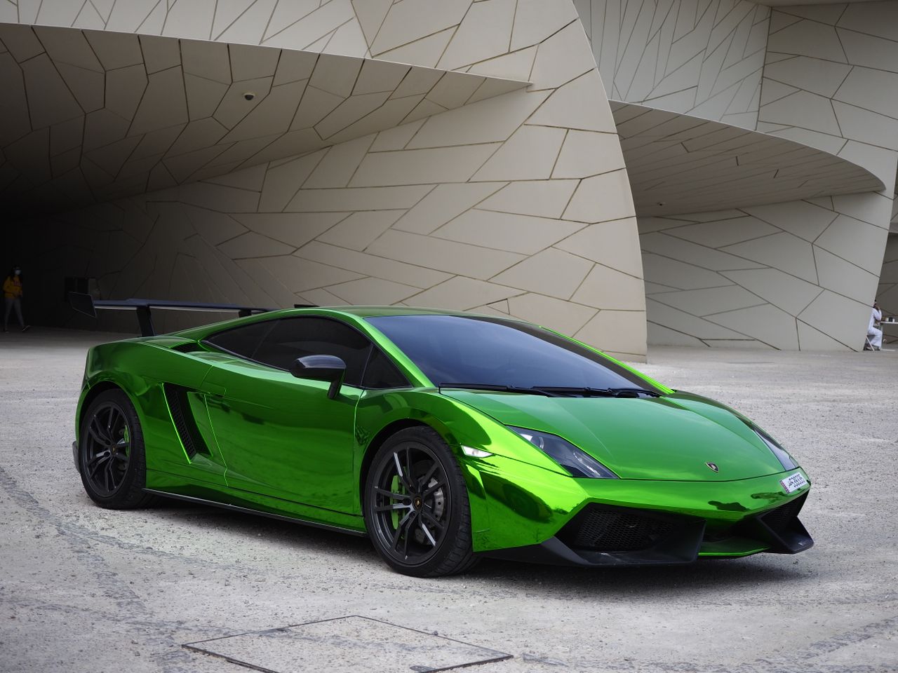 shiny green sports car parked outside modern architecture in doha qata