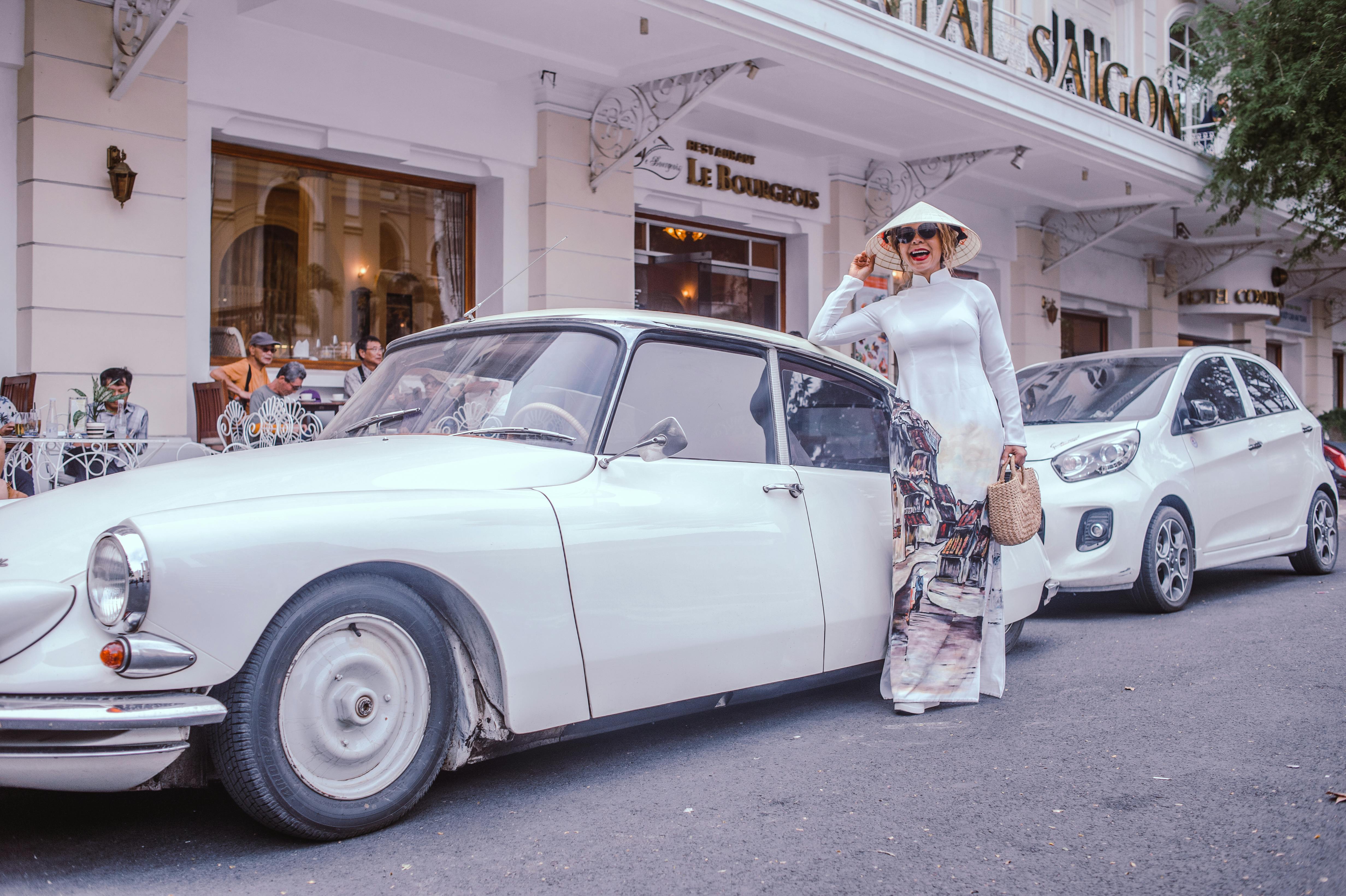 woman standing beside classic white sedan