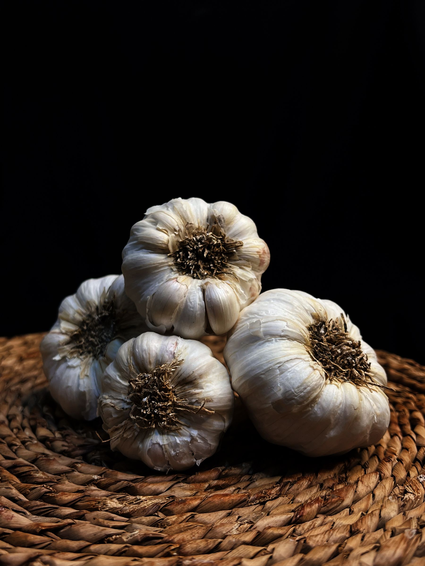 White garlic bulbs on a woven surface