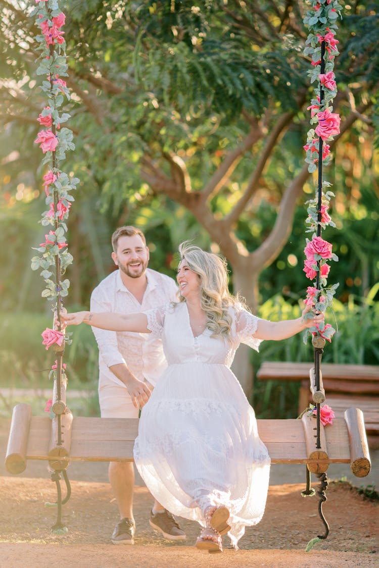 A Man Pushing The Woman Sitting On A Swing