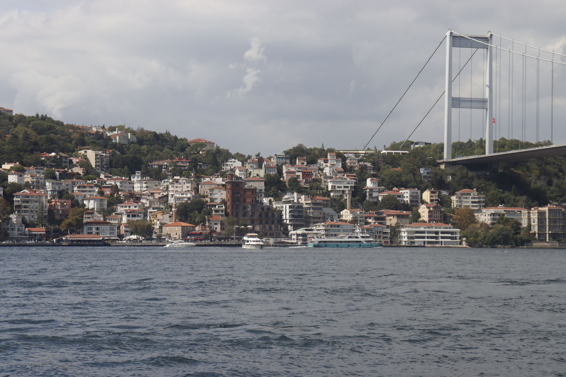 Picturesque Istanbul waterfront with homes and the Fatih Sultan Mehmet Bridge across the Bosphorus.