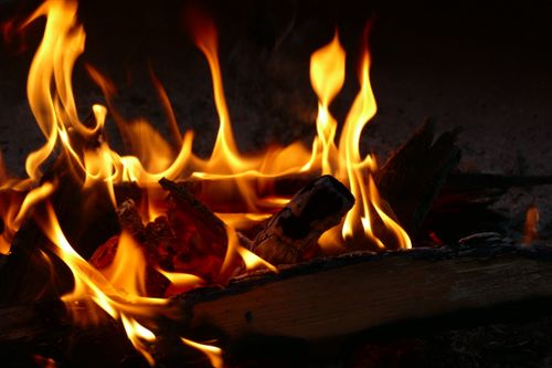 Free Warm and inviting close-up of a flickering campfire with glowing flames and embers. Stock Photo