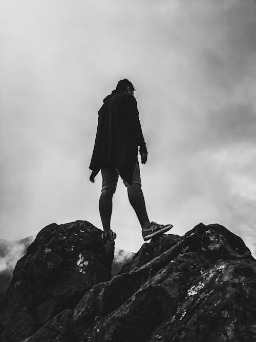 Man Standing on Rocks in Black and White