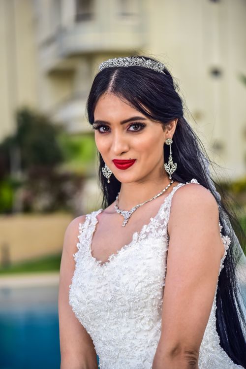 Free A beautiful bride poses outdoors in a stunning wedding gown, showcasing elegant bridal jewelry and hairstyle. Stock Photo