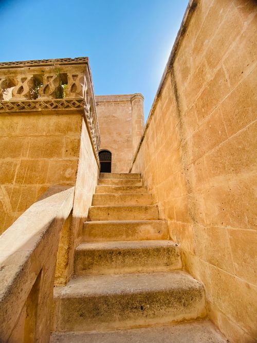 Free Sunlit stone stairs ascend to an ancient building with architectural details. Stock Photo