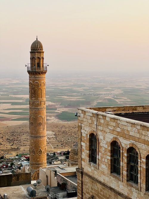 Free Vertical view of minaret in Mardin, Turkey, with expansive rural landscape at sunset. Stock Photo