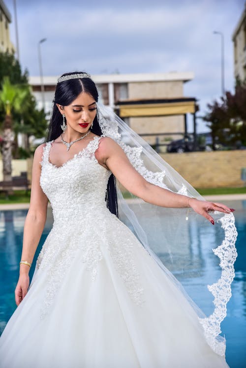 Woman in a White Wedding Dress Standing Near a Body of Water