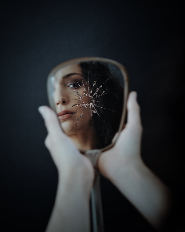 Woman Looking In Broken Mirror