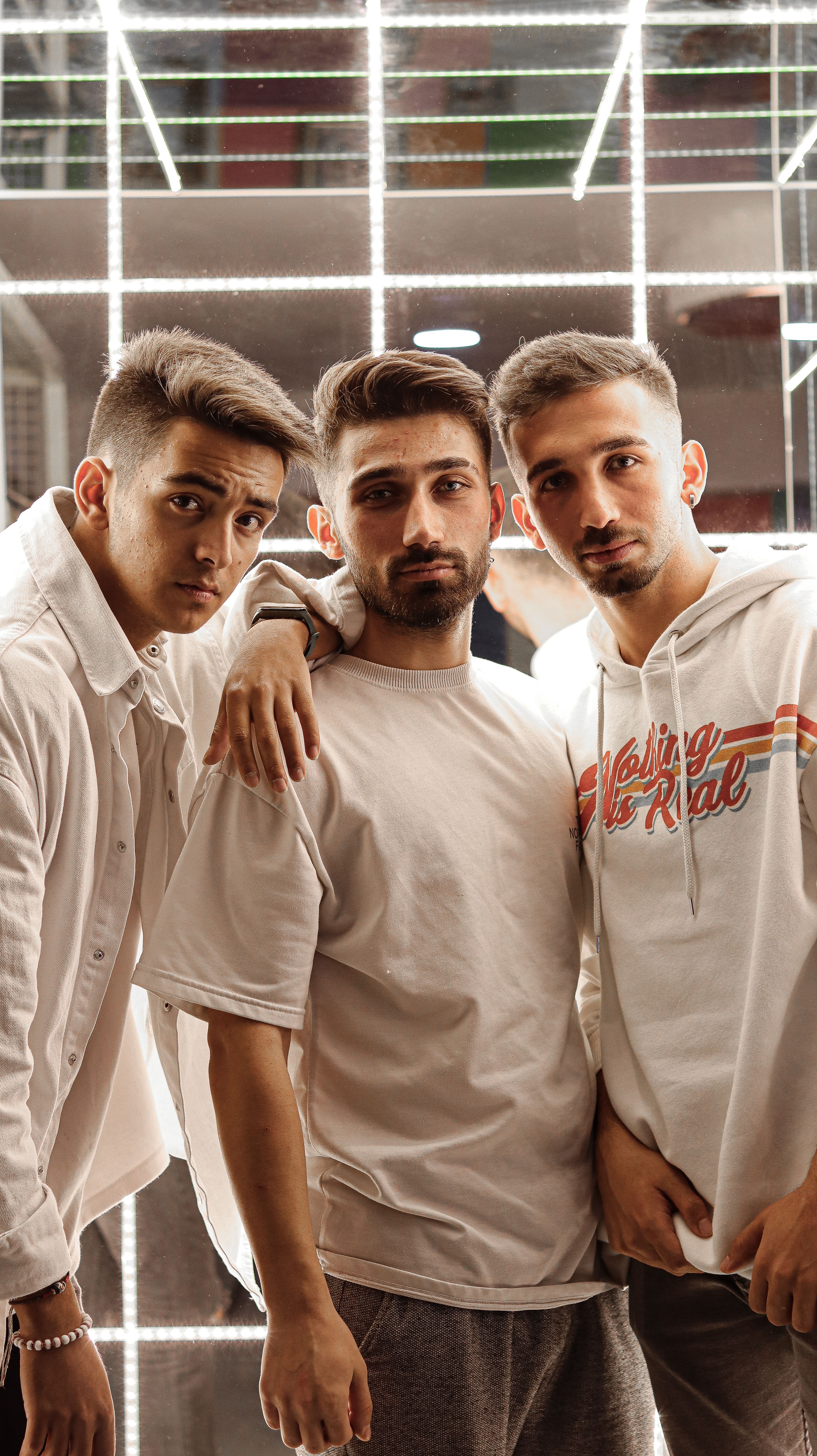 Three stylish young men posing indoors with illuminated background lighting in Edirne, Türkiye.