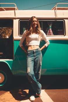 Smiling woman leans on a retro van in summer, embodying vintage style and carefree travel vibes.