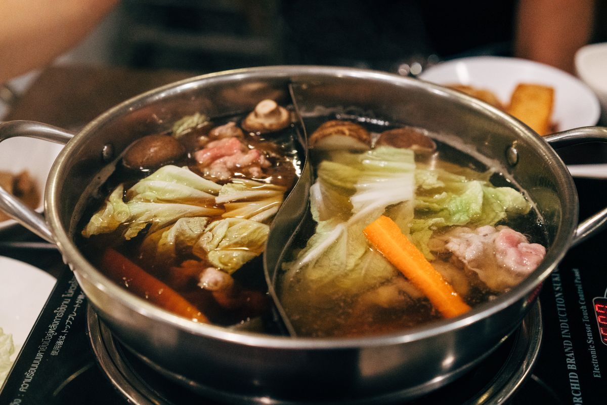 Steaming Japanese sukiyaki hot pot filled with beef, tofu, mushrooms and vegetables in sweet soy sauce