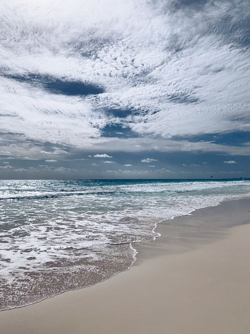 Free Tranquil beach and cloudy sky at Cancún. Perfect for travel and relaxation images. Stock Photo