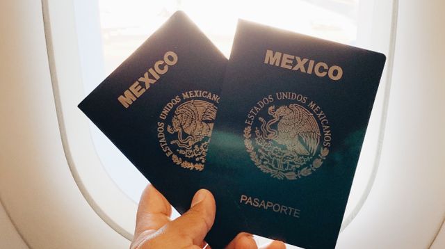 Hand holding passports beside an aeroplane window