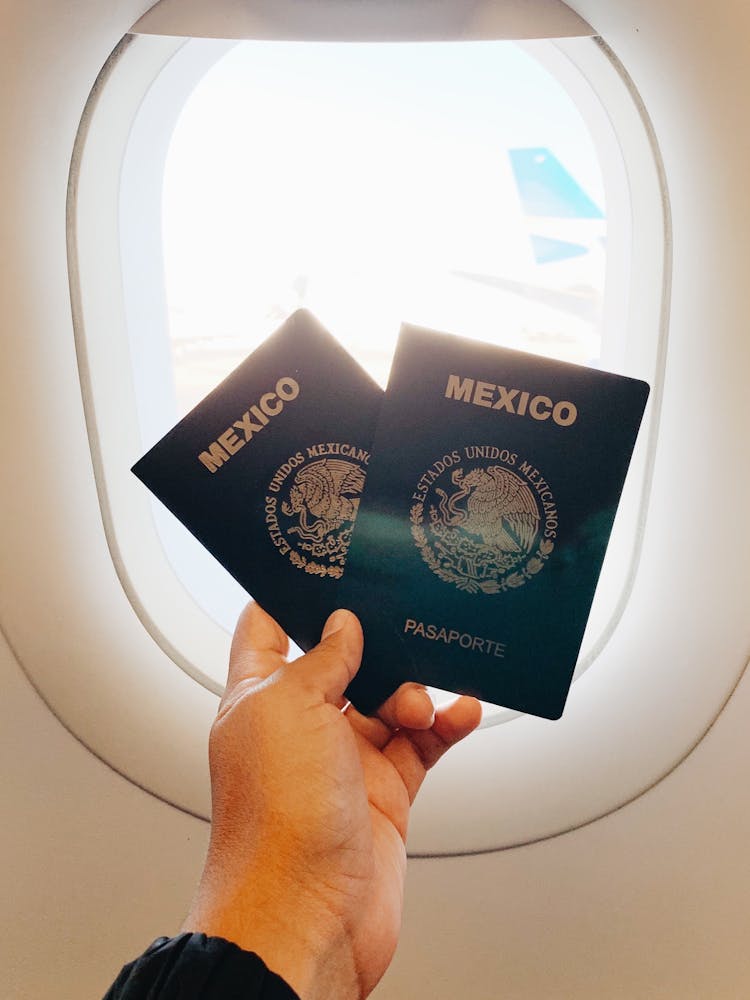 Hand Holding Passports Near Plane Window