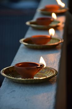 Clay lamps, or diyas, beautifully lit on a railing for a festive glow.