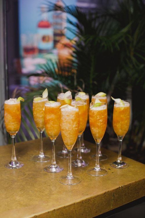 Free A set of vibrant orange cocktails with lime garnishes on a golden table in Cape Town. Stock Photo