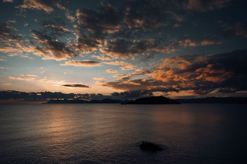 Free A tranquil sunset scene over the ocean, showcasing dramatic clouds and a peaceful twilight sky. Stock Photo
