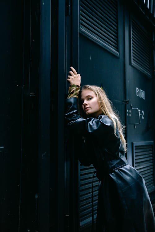 Woman in Black Leather Coat Leaning on a Wall