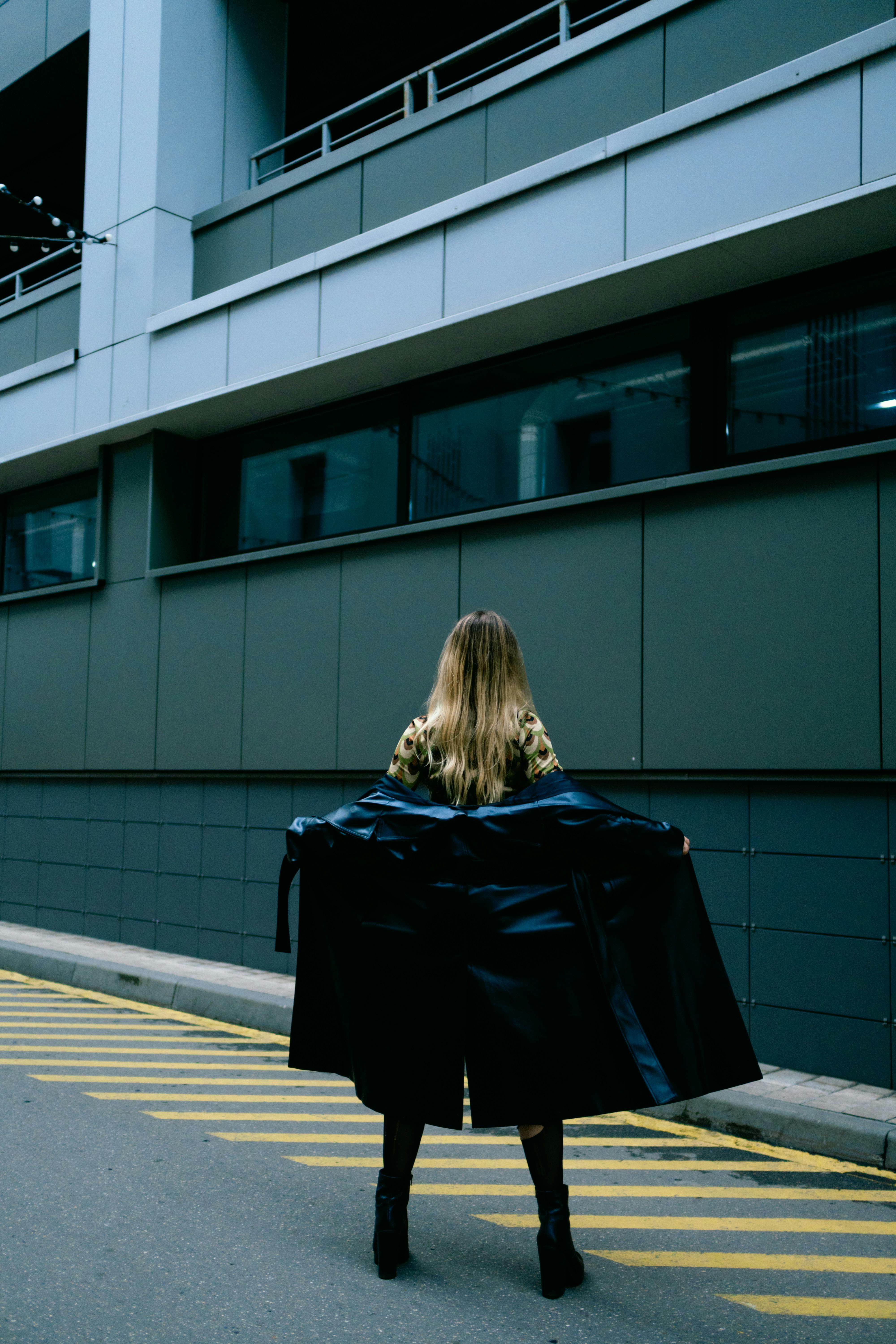 Free Back view of a stylish woman in a black jacket on an urban street. Stock Photo