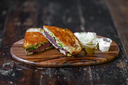 A griddled sandwich on a wooden board. Photo by Daniel Torobekov on Pexels.
