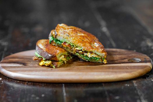 Tasty rustic sandwich filled with fresh ingredients on a wooden cutting board.