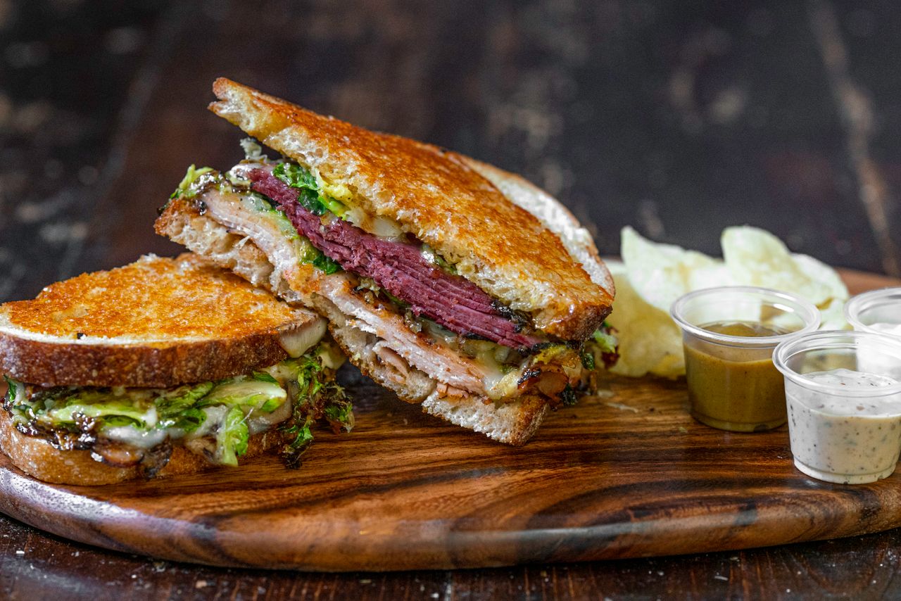 Sandwich stacked with roast beef and fresh lettuce on a wooden serving board