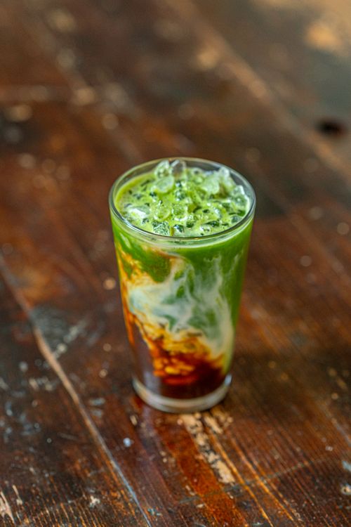 Free A vibrant iced matcha latte with a swirling cream effect, set on a rustic wooden table. Stock Photo