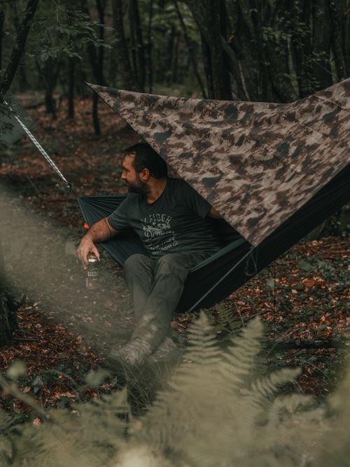 Free A man enjoys a peaceful moment in a hammock with a beer in a lush forest setting. Stock Photo