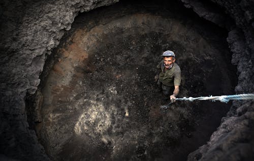High Angle View of Laborer in a Huge Hole Holding a Rope 