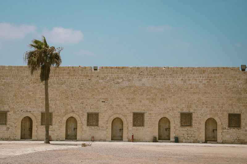Sandstone fortress wall lined with arched doorways — photo by Andreea Ch on Pexels