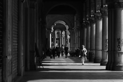 Free Black and white image of a historical arched walkway with people walking in Turin, Italy. Stock Photo
