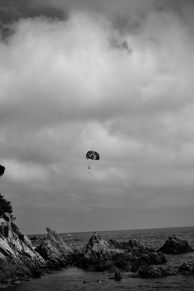 Grayscale Photo Of Parasailing On The Beach