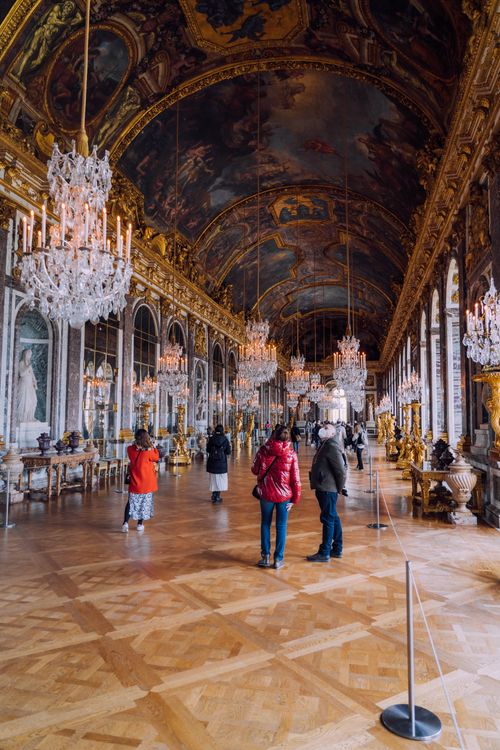 Free Opulent interior of the Hall of Mirrors in Versailles with chandeliers and tourists admiring the architecture. Stock Photo