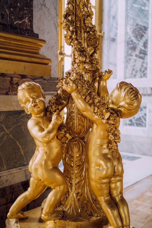 Free Intricate golden cherub statues decorate the opulent interiors of Versailles Palace, France. Stock Photo