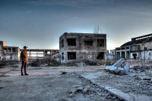 Человек, стоящий возле разрушенных зданий