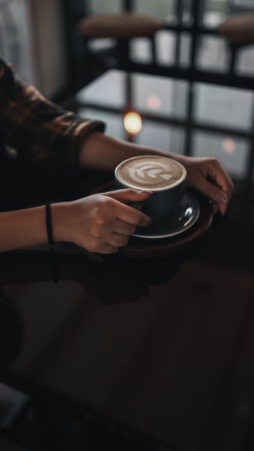 Free A person enjoying a beautifully crafted latte art in a cozy café setting, reflecting a moment of relaxation. Stock Photo