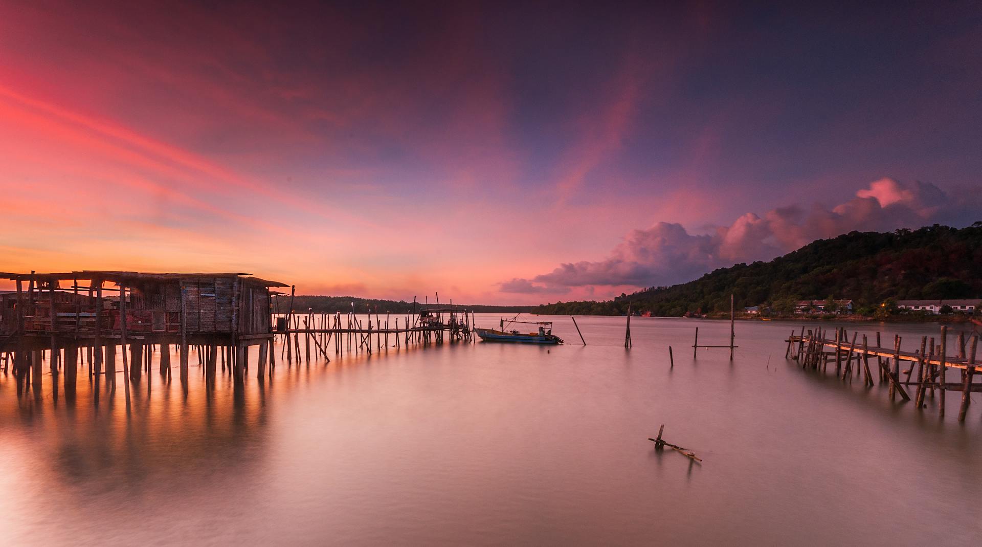 Stunning view of a tranquil pier at sunset with vibrant skies reflecting on calm waters.