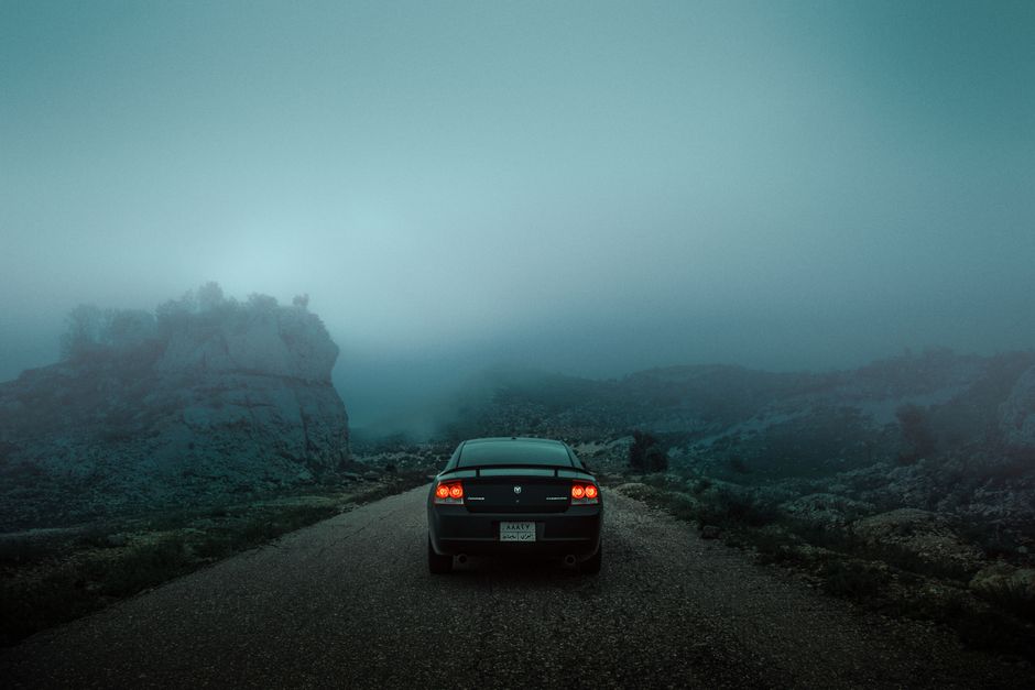 Car on a misty mountain road in Dihok, Kurdistan Region, Iraq, capturing a moody and dramatic atmosphere.