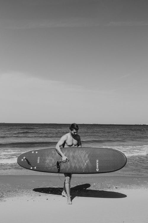 Grayscale Photo of a Surfer at the Beach