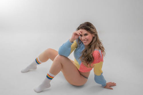 Sexy Woman in Colorful Sweater Sitting on the Floor