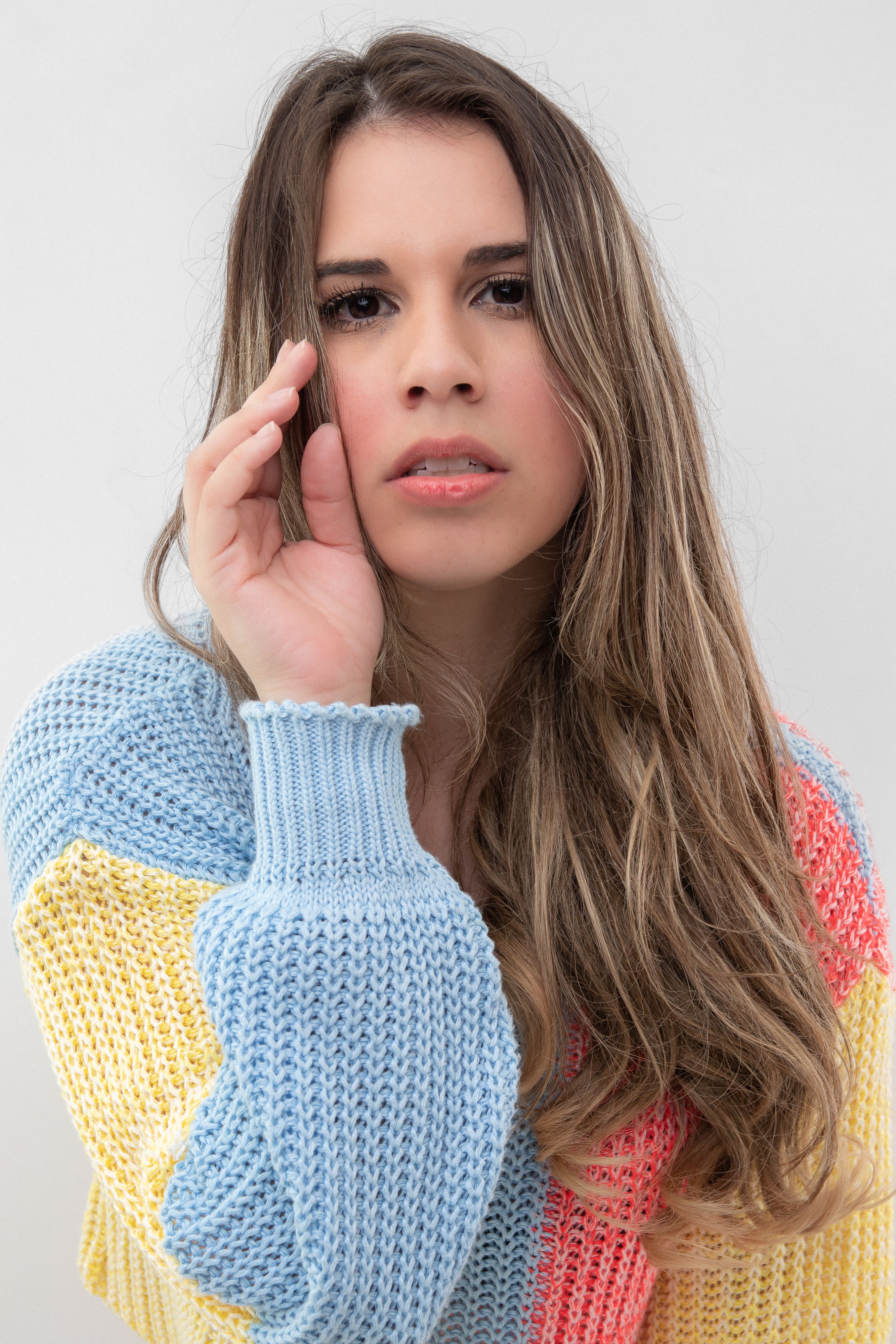 A woman posing confidently in a pastel knitted sweater, exuding fashion and style.