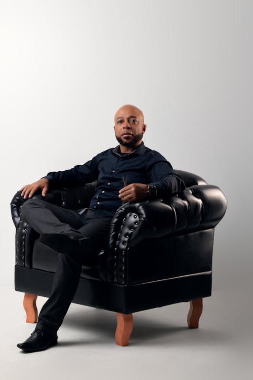 Photo of a Man Sitting on a Black Armchair