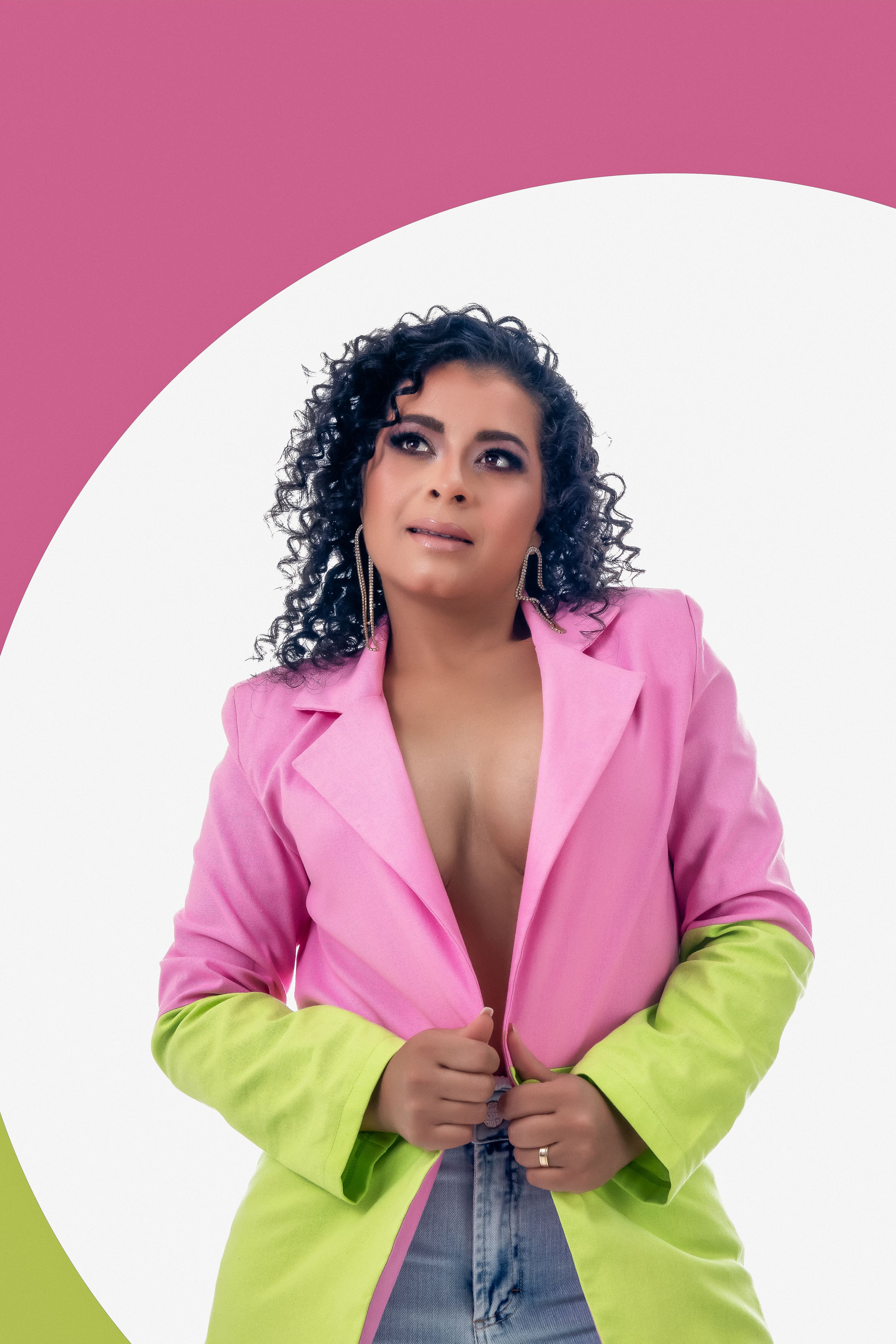 Elegant woman posing in a vibrant pink and green blazer against a bold geometric background.
