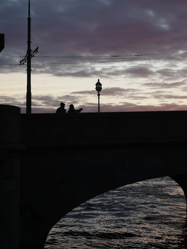 Silhouette Of People Walking On Bridge On Sunset