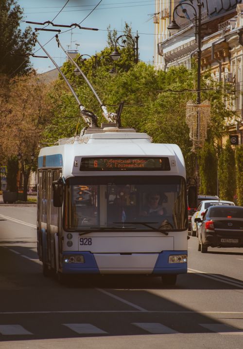 Free Trolleybus traveling on a city street with cars during the day, showcasing urban transportation. Stock Photo