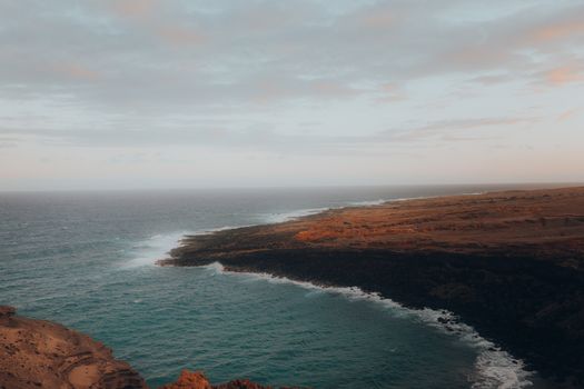 A breathtaking view of a rugged coastline with waves crashing against the shore during twilight.