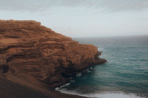 Free Dramatic coastal cliff with rugged textures overlooking the serene ocean on a clear day. Stock Photo