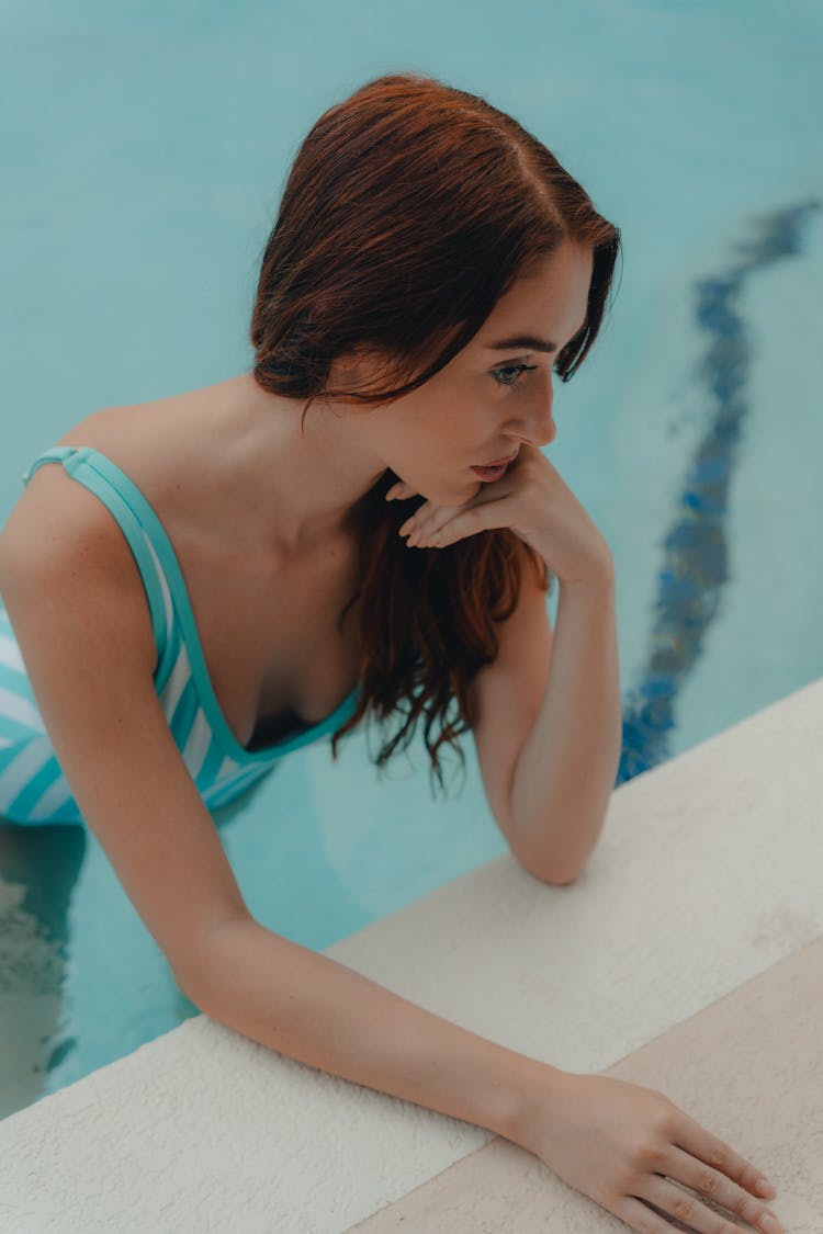 Redhead Woman Leaning On The Edge Of A Swimming Pool 